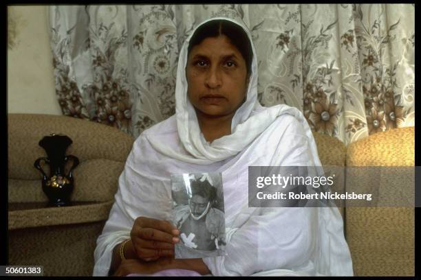 Mother w. Pics of her sons as victims of drive-by shooting, 1 killed, 1 losing leg in 1 of daily incidents of sectarian violence in lawless Karachi,...