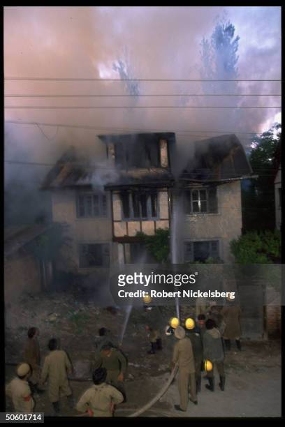 Firemen hosing burning home in violent aftermath of burning of Charar-e-Sharief Muslim shrine in Kashmiri separatists vs. Indian troops battle. Near...