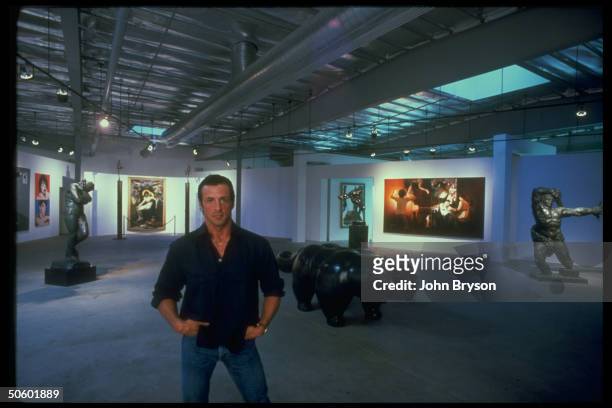 Actor Sylvester Stallone in lobby of office in front of his art collection, incl. Eve by Rodin, Two Sides of Sly by Warhol, Bouguereau's Pie.