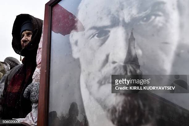 Russian Communist Party supporter holds a portrait of late Soviet leader Vladimir Lenin as he takes part in a memorial ceremony to mark the 92st...