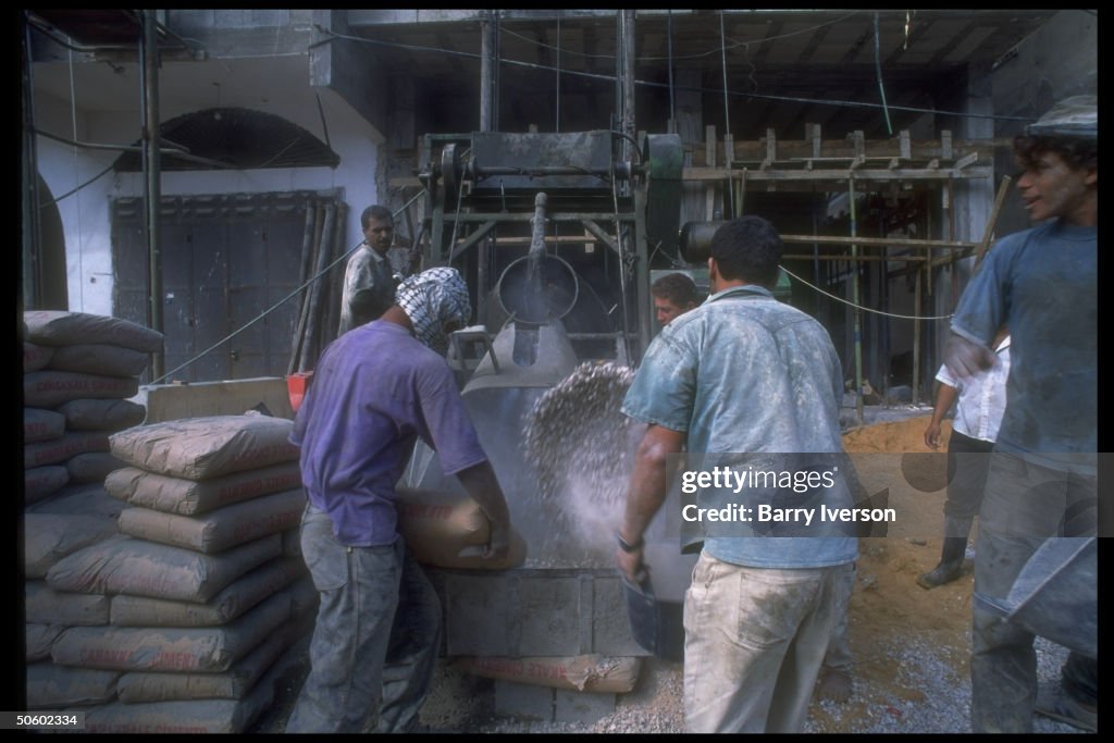 Workers mixing cement on site of highris