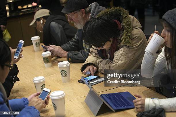 Customers use mobile devices inside a Starbucks Corp. Coffee shop in New York, U.S., on Monday, Jan. 18, 2016. Starbucks Corp. Is scheduled to...