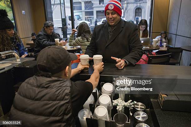 Customer receives beverages from a barista inside a Starbucks Corp. Coffee shop in New York, U.S., on Monday, Jan. 18, 2016. Starbucks Corp. Is...