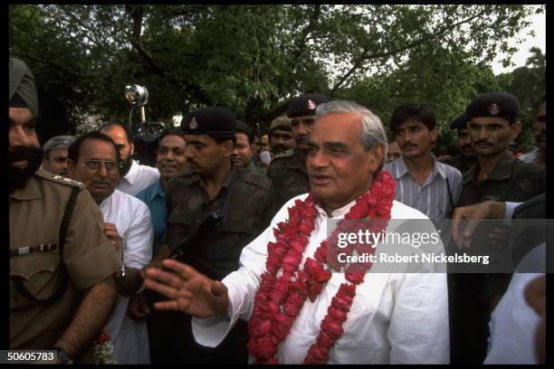 New PM BJP ldr. A.B. Vajpayee, garlanded, framed by security & supporters in post-election celebration of opposition ascent to power.
