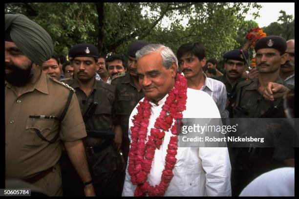 New PM BJP ldr. A.B. Vajpayee, garlanded, framed by security & supporters in post-election celebration of opposition ascent to power.