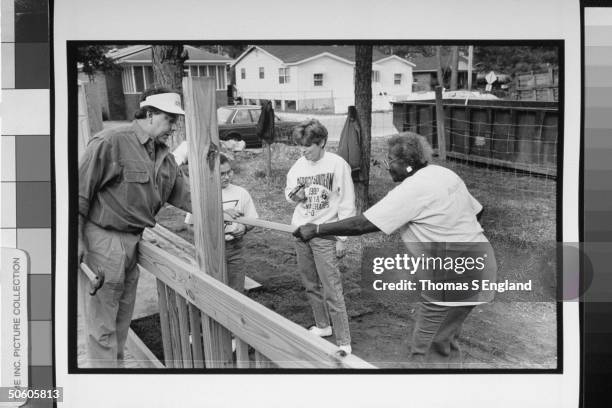 Annie Mae Rhodes former nanny & housekeeper to former Pres. Jimmy Carter, handing wooden post to Habitat for Humanity volunteer Eddie Douglas as his...