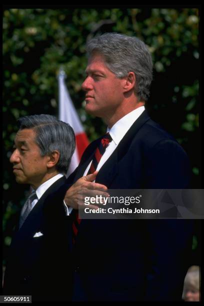 Pres. Bill Clinton poised w. Hand-over-heart, standing w. Japanese Emperor Akihito as natl. Anthem plays during WH S. Lawn arrival ceremony.