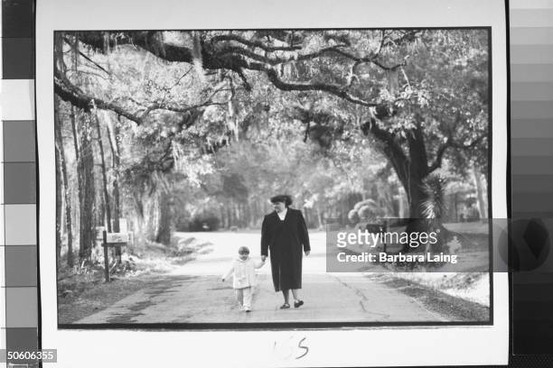 Gamete intrafallopian transfer baby Judith Hart holding hands w. Mother Nancy as she walks down peaceful tree-lined road nr. Home; Social Security...