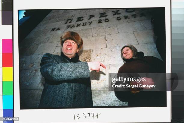Duma cand. Ultranationalist Liberal Dem. Party ldr. Vladimir Zhirinovsky gesturing to old babushka, talking to woman while out campaigning on streets...