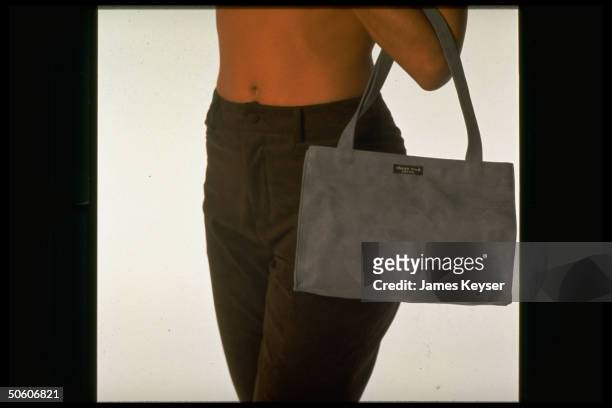 Ultrasuede pants-clad model carrying faux suede handbag by designer Kate Spade re synthetic's revival in fall fashions.