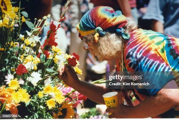 Tie-dye-clad hippie icon Hugh Wavy Gravy Romney leaning over to smell boquet of flowers during memorial service for Grateful Dead front-man Jerry...