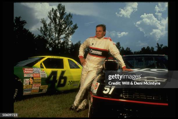 Racing team owner J.R. Rick Hendrick, owner of 4 auto-racing teams, posing w. Two cars that appeared in film Days of Thunder.