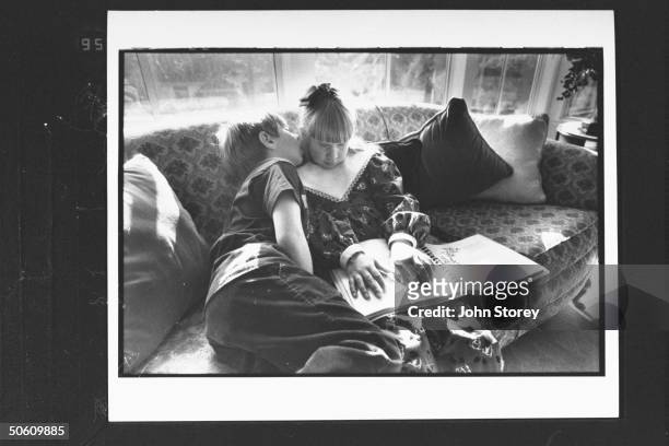 Blind girl Elizabeth Phillips who was shaken violently & blinded by babysitter Colette Andrews sitting on sofa reading braille book while her brother...