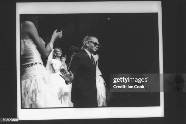 Fashion designer Karl Lagerfeld w. Model Claudia Schiffer wearing one of his creations & clapping behind him at Chanel spring show.