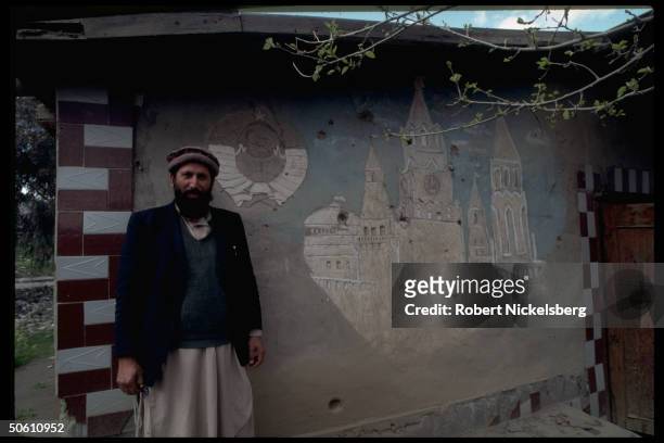 Mujahedin by former Soviet barracks facade mural depicting Soviet seal & Kremlin scene, in largely ethnic Pathan, Salafiya rebel-held Kunar province.