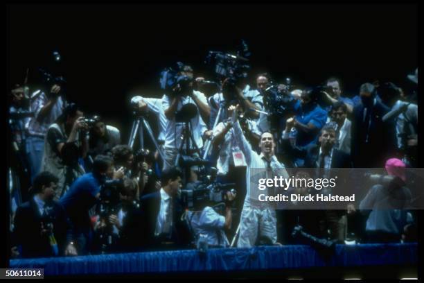 Activist, surrounded by reporters & cameramen in press box, waving unrolled condom, heckling Pres. Bush during Repub. Natl. Convention rally in...