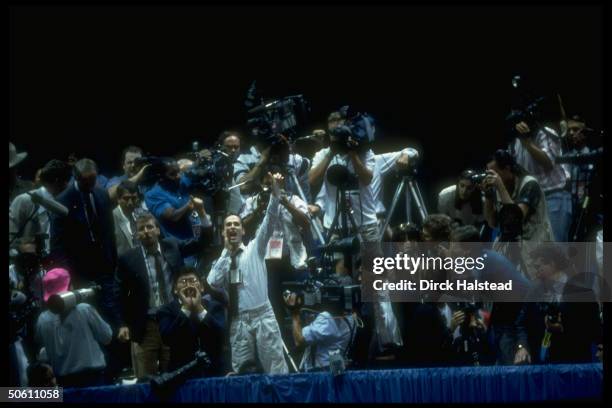 Activist, surrounded by reporters & cameramen in press box, waving unrolled condom, heckling Pres. Bush during Repub. Natl. Convention rally in...