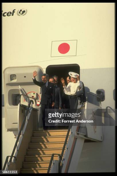 Japanese Emperor Akihito & Empress Michiko waving, poised in doorway of their Unicef-logo'ed JAL jet, coming or going, visiting Beijing, China.