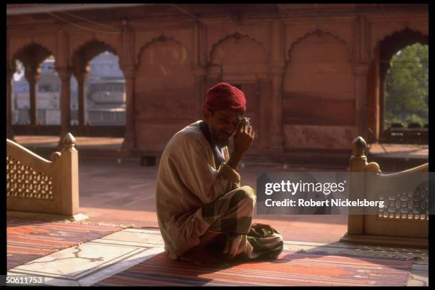 Muslim on prayer rug in mosque-type yard, crying over rampage by Hindu mobs burning Muslim homes & mosque in riots re Hindu razing of Ayodhya Babri...