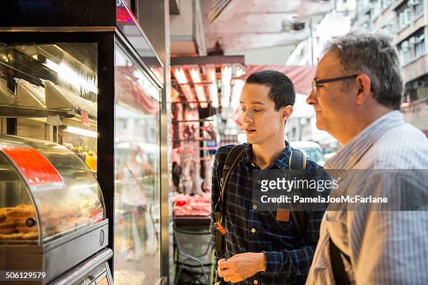 two men looking at egg tarts at a chinese bakery - hong kong community 個照片及圖片檔