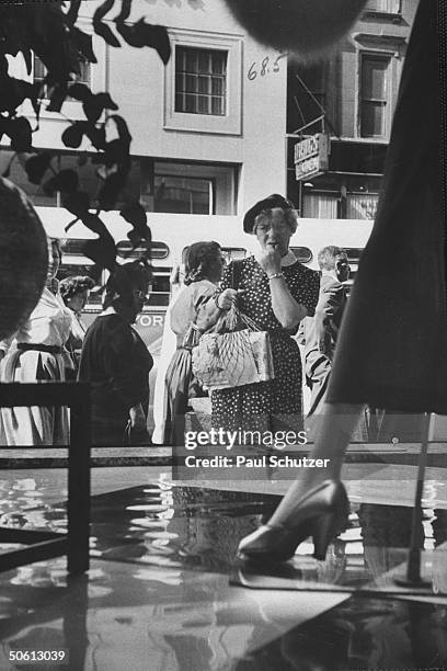 Older woman looking worried as she gazes into Bloomingdale's window, where Dior-inspired longer skirts are being displayed.