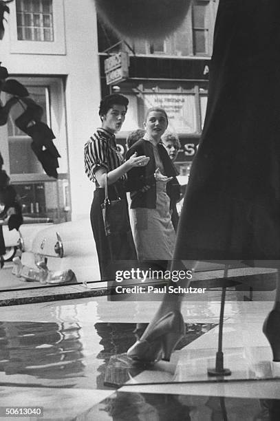 Women looking somewhat skeptical as they gaze into Bloomingdale's window, where Dior-inspired longer skirts are being displayed.