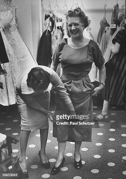 Store buyer holding up hemline a bit as older woman tries on dress w. New longer length skirt, inspired by designer Christian Dior, at Bloomingdale's.
