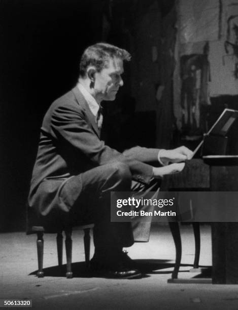 Avant-garde minimalist composer John Cage playing a children's size piano.