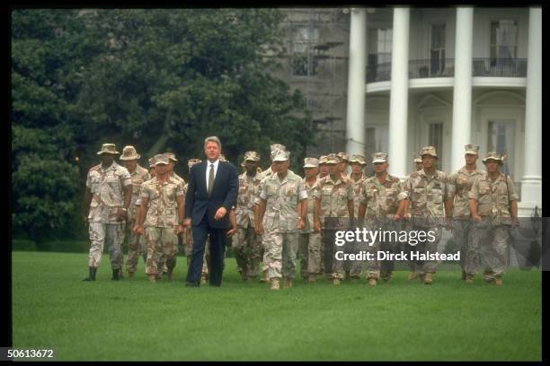 President Bill Clinton with a contingent of camouflage-clad Marine and Army soldiers recently returned from Somalia, during a ceremony honoring...