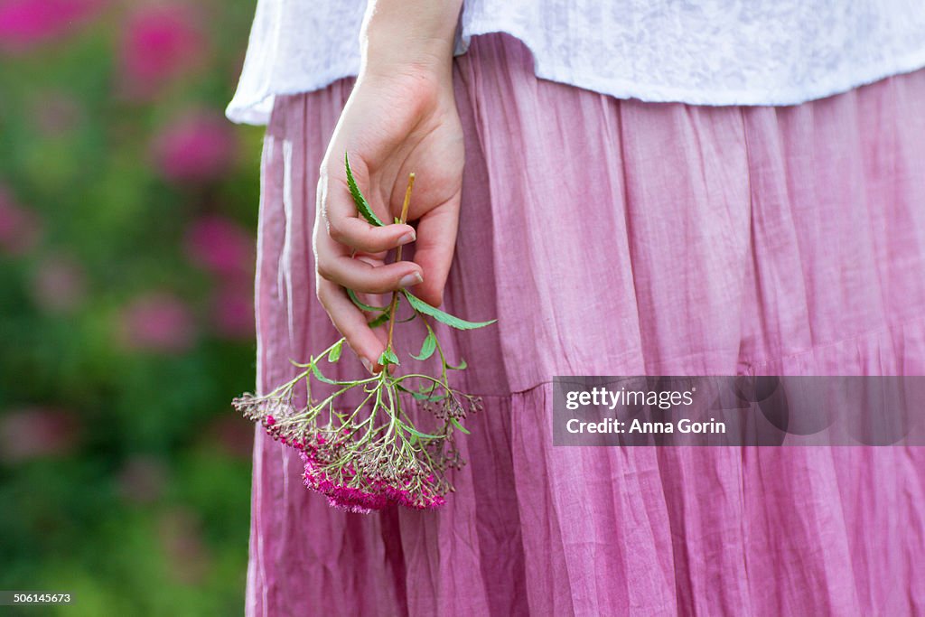 Closeup on woman's hand holding flowers by skirt