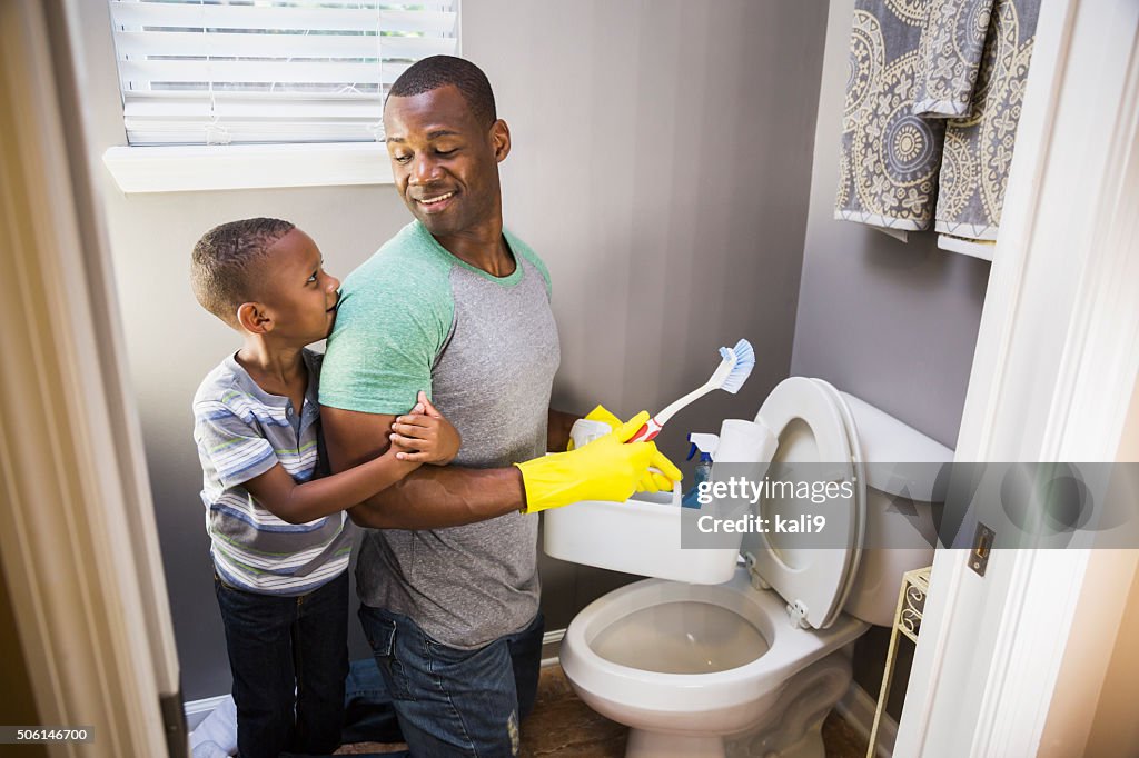 African American man with son, cleaning bathroom toilet