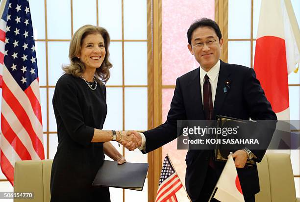 Japan's Foreign Minister Fumio Kishida shakes hands with US Ambassador to Japan Caroline Kennedy after attending a signing ceremony for the Host...