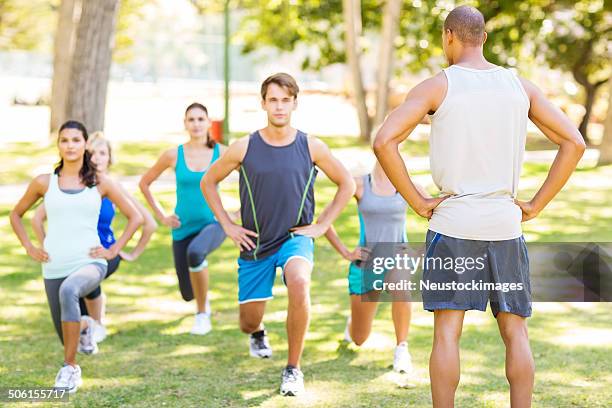 instructor looking at people doing lunges in park - military camp stock pictures, royalty-free photos & images