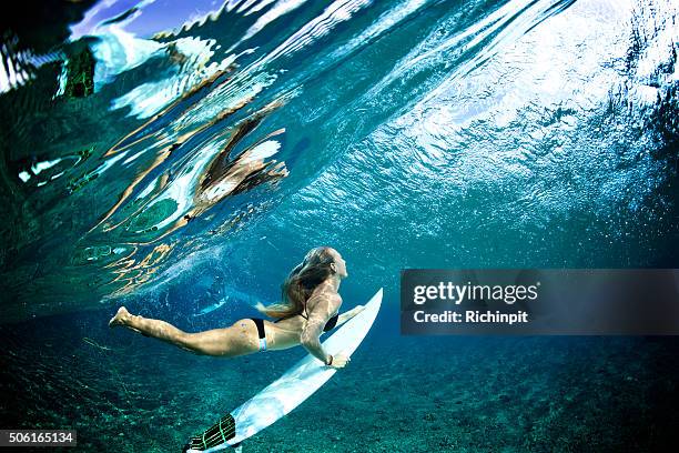 surfer girl duckdives a wave with reflection - surf girl stock pictures, royalty-free photos & images