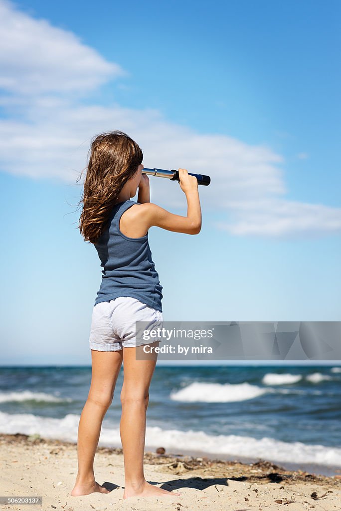 Girl looking at the sea with a telescope
