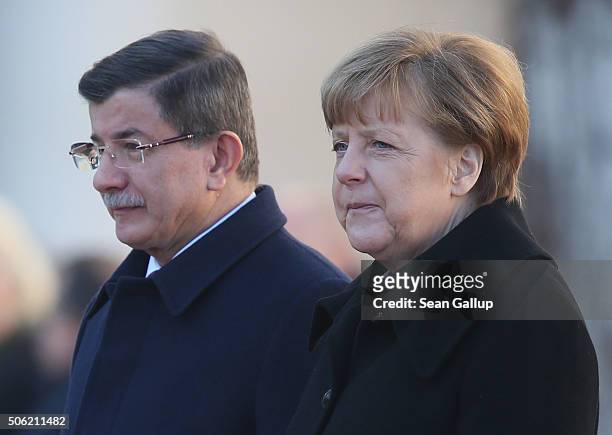 Turkish Prime Minister Ahmet Davutoglu and German Chancellor Angela Merkel listen to their countries' respective national anthems following...