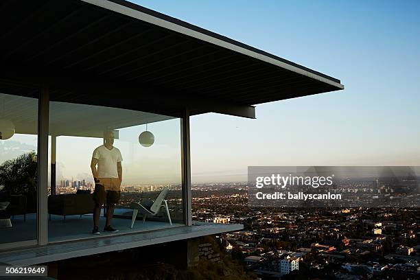 man standing in house overlooking los angeles. - asset protection stock pictures, royalty-free photos & images