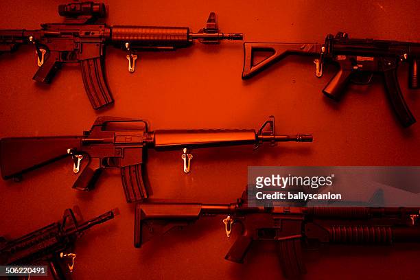 numerous assault rifles hanging on wall. - guns ストックフォトと画像