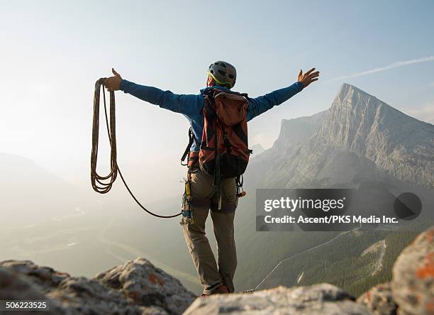 climber stands on summit rocks, arms outstretched - top fotografías e imágenes de stock