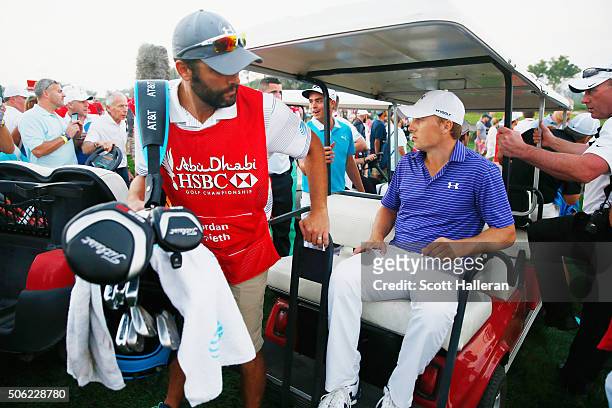 Jordan Spieth of the United States and his caddie Michael Greller load into a cart after play was suspended by darkness during the second round of...