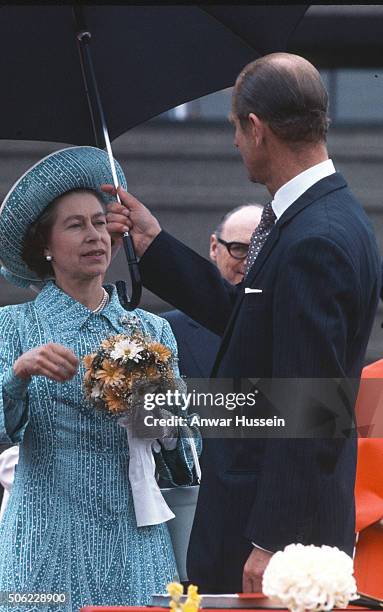 Prince Philip, Duke of Edinburgh hold an umbrella to shelter Queen Elizabeth ll from the rain during a tour of Canada on July 01, 1976 in Canada.