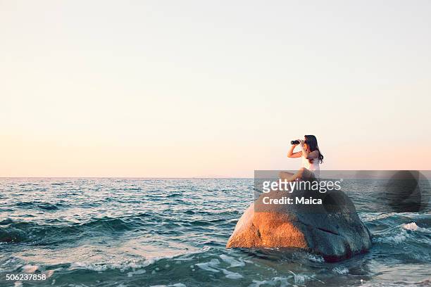 looking with binoculas on top of a bouder - beach girl stock pictures, royalty-free photos & images