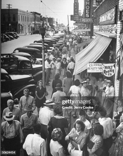 View looking down on Commercial St. Of Lebanon, with cars parked on both sides of a street and pedestrian walking along while shopping.