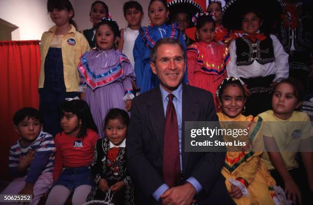 Incumbent Repub. Gov. George W. Bush posing w. Hispanic children during re-election campaign rally.