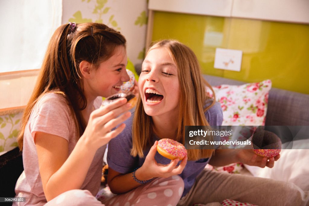 Girls having a fun pyjama party with colourful doughnuts