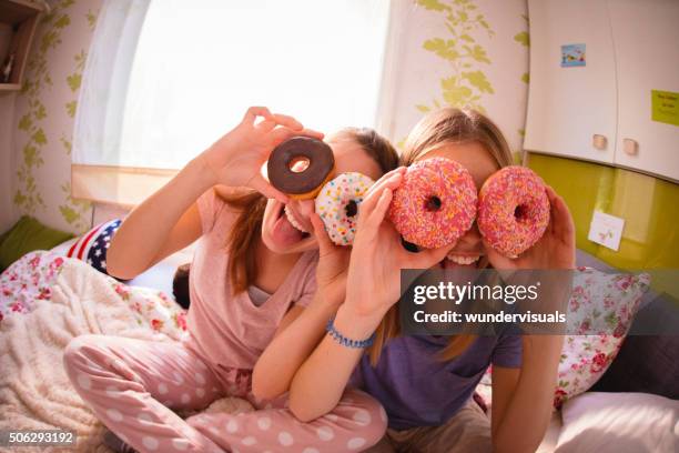 teenager-mädchen mit bunten donuts auf ihre augen - girls sleepover stock-fotos und bilder