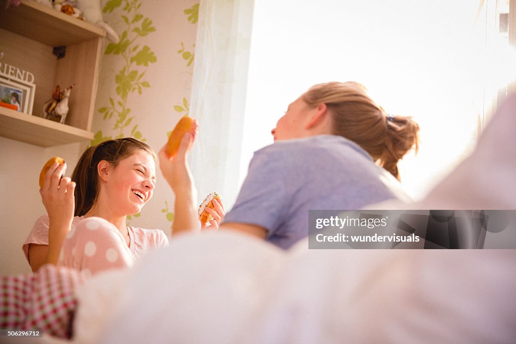 10 代の少女の笑顔とドーナツを食べるのベッドルーム