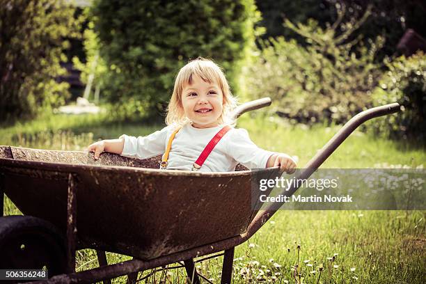 child in wheelbarrow - wheelbarrow stock pictures, royalty-free photos & images