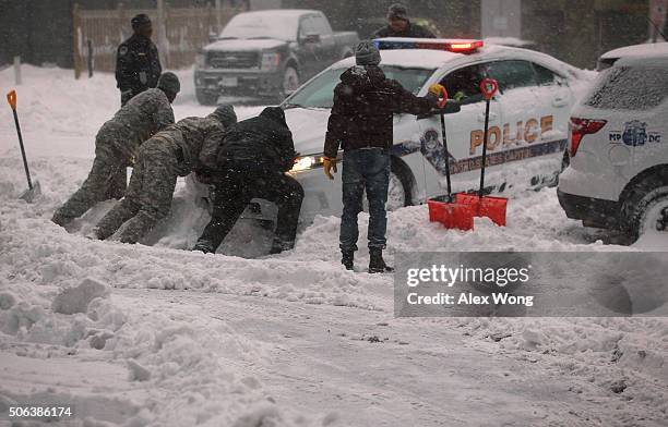 National Guard members and other people help to push a police car, which got stuck in the snow on January 23, 2016 in Washington, DC. Heavy snow...