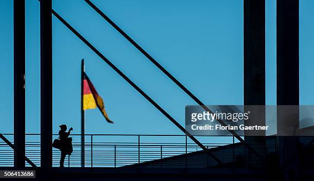 Woman takes a picture on a bridge in front of the german national flag on January 22, 2016 in Berlin.